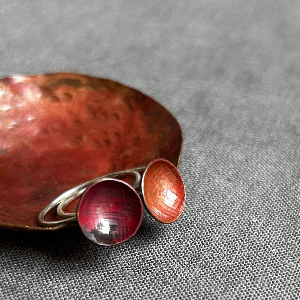 Two red copper circle rings on a textured gray surface