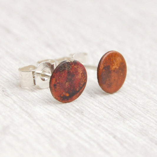 A pair of stud earrings, a small disk of heat coloured copper with silver posts and butterfly backs, by zoe ruth designs.