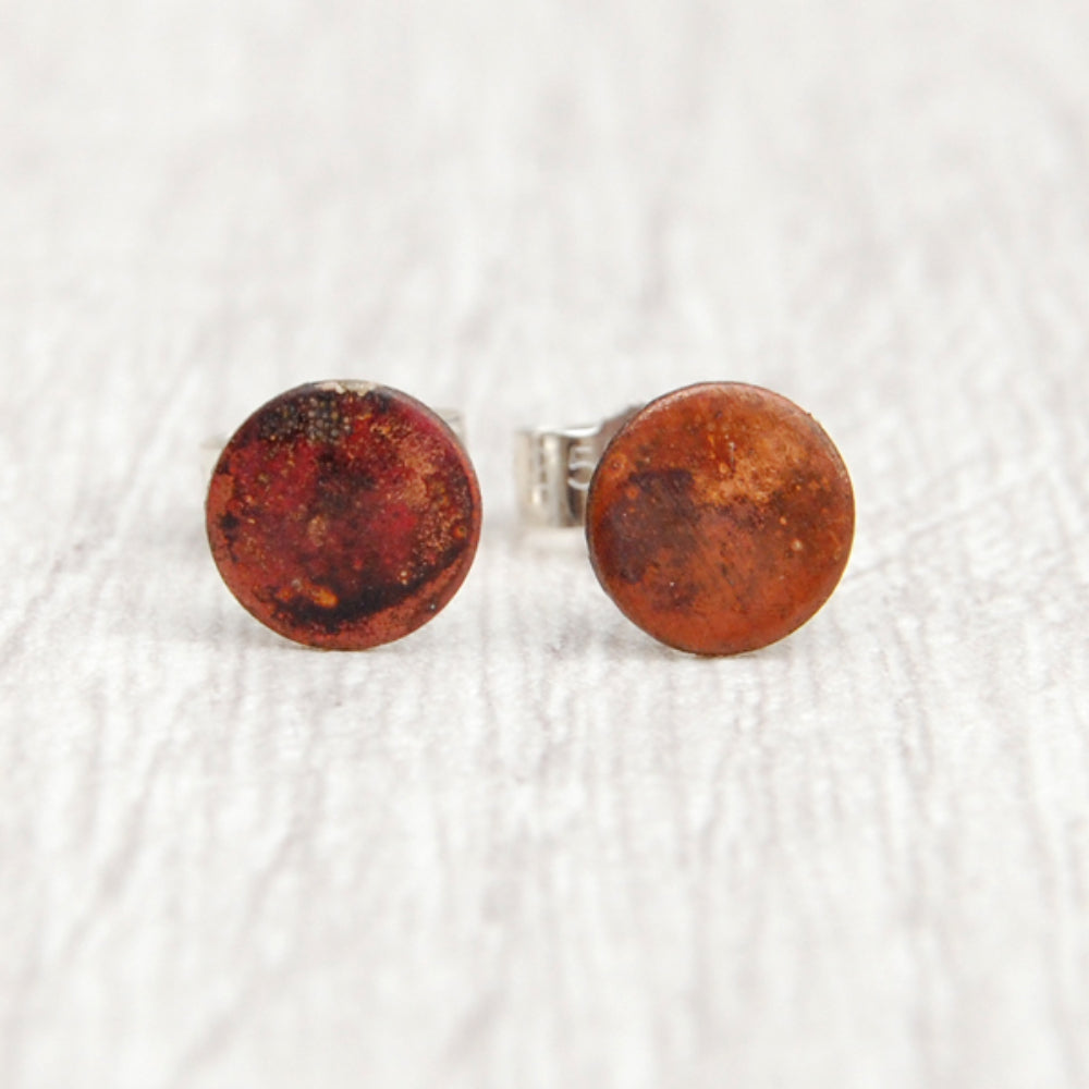 A pair of stud earrings, a small disk of heat coloured copper with silver posts and butterfly backs, by zoe ruth designs.