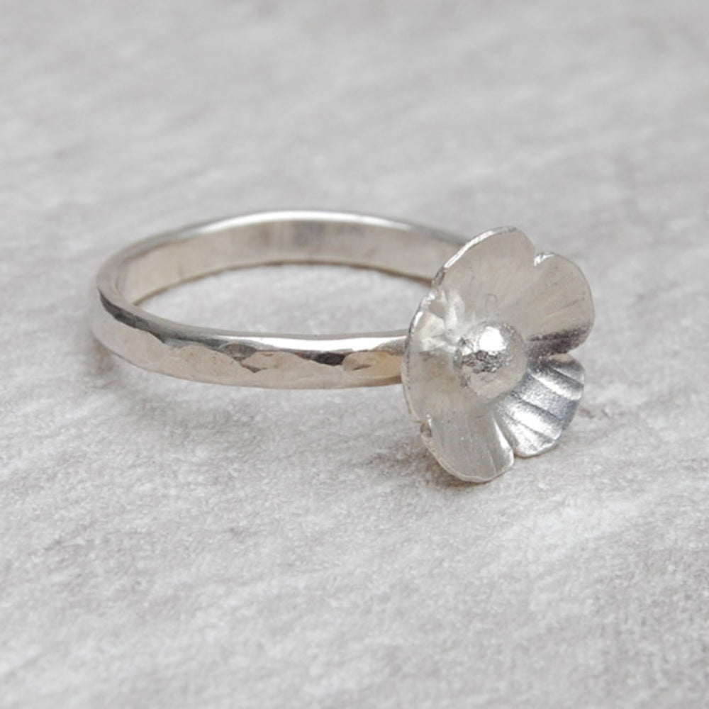 A five petaled silver flower sits on a hammered silver slim ring, by zoe ruth designs