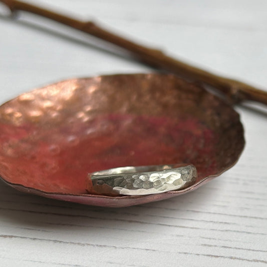 A classic dimple hammer texture on a D profile silver ring, sat in a copper dish, by zoe ruth designs