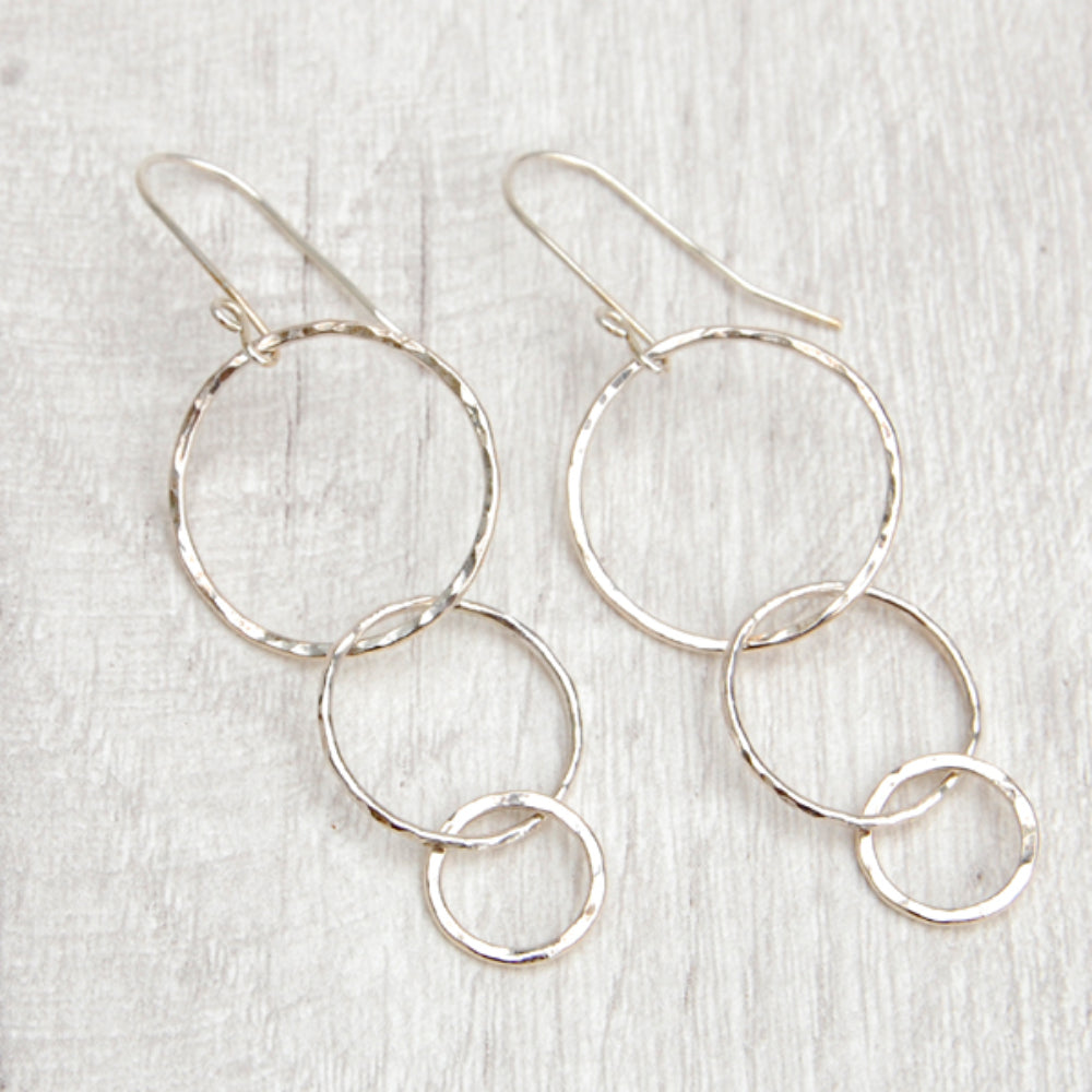 Three silver open circles of decreasing sizes hang from the silver earring hooks, by zoe ruth designs.