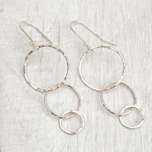 Three silver open circles of decreasing sizes hang from the silver earring hooks, by zoe ruth designs.