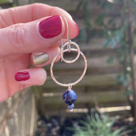 A single handmade silver hook earrings, with hammered silver circles, the smaller layered over the larger, and two Lapis Lazuli stones hanging underneath, by zoe ruth designs