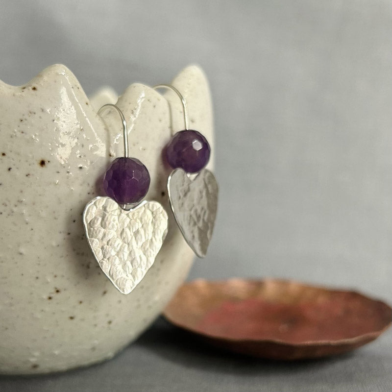 classically hammered sterling silver hearts with a faceted Amethyst round stone sat above them on silver earring wires.