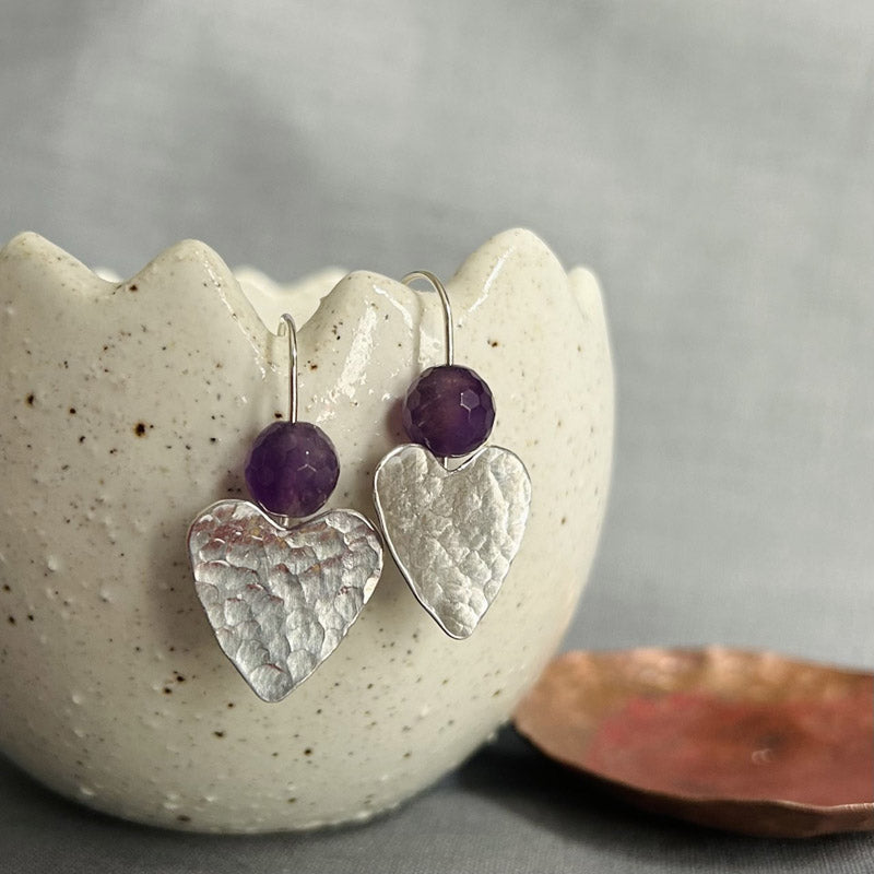 classically hammered sterling silver hearts with a faceted Amethyst round stone sat above them on silver earring wires.