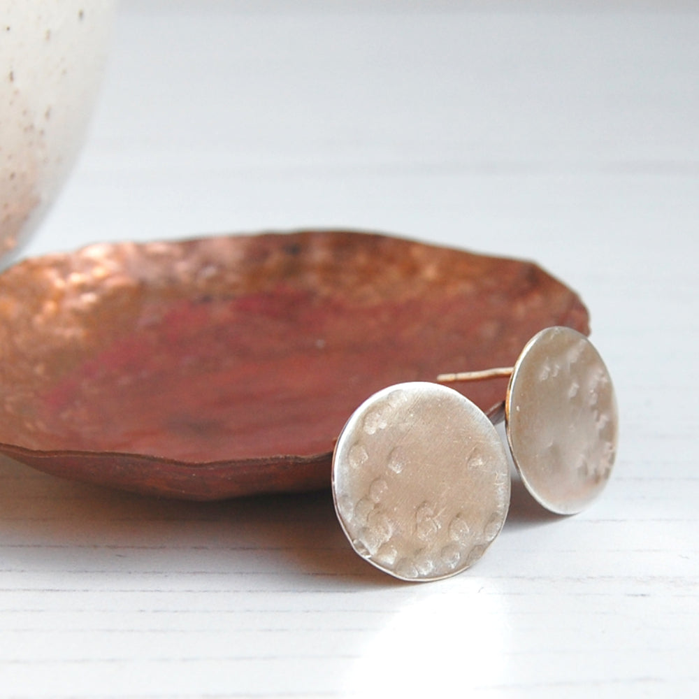 A pair of silver disk shaped stud earring with some gentle hammer marks to suggest craters on a full moon surface, by zoe ruth designs