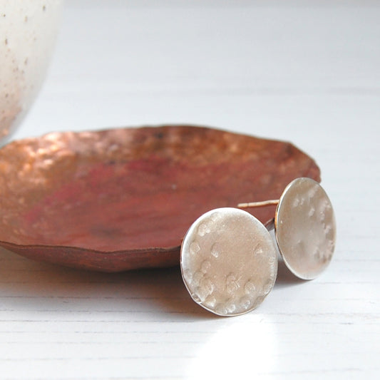 A pair of silver disk shaped stud earring with some gentle hammer marks to suggest craters on a full moon surface, by zoe ruth designs