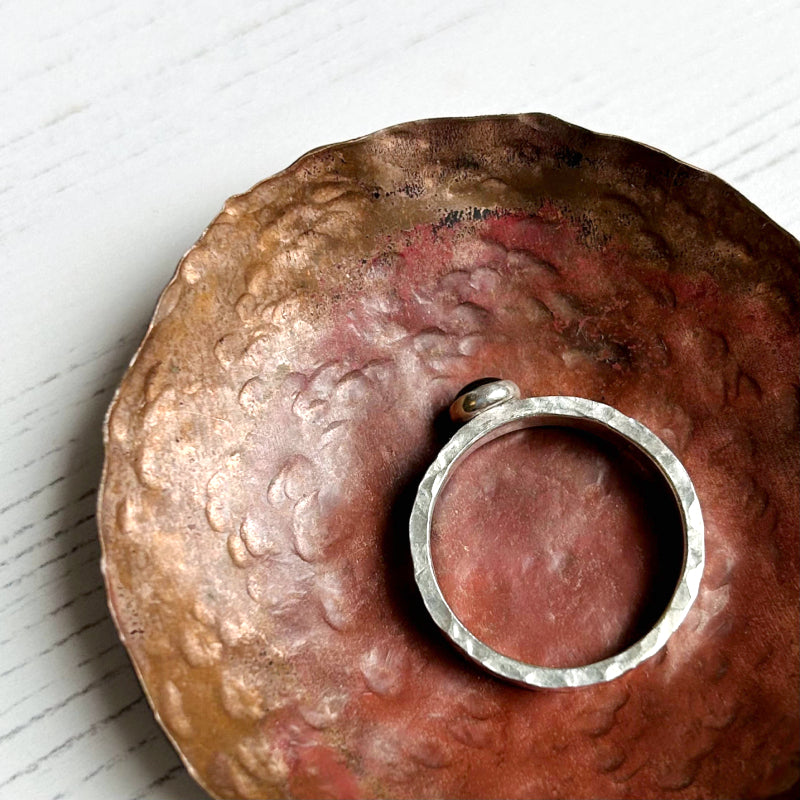 showing this handmade ring has texture on the edge of its thick silver band