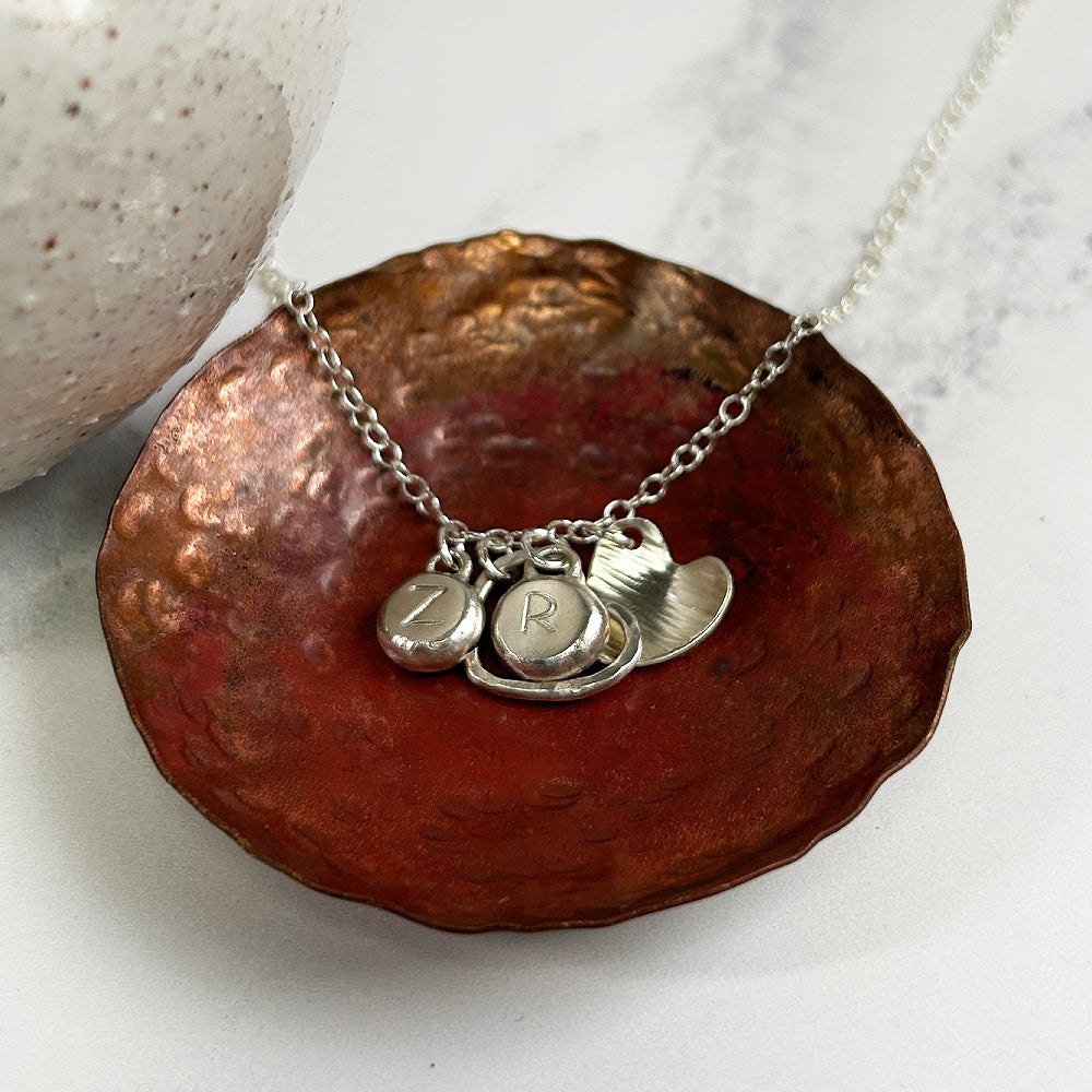 Necklace of handmade silver hearts and two silver pebbles with the letters Z and R stamped by zoe ruth designs