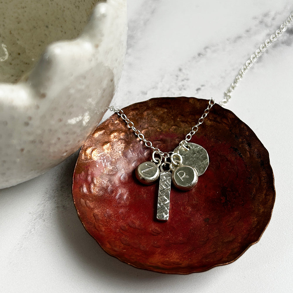 Silver charms necklace with a textured bar, disk and two silver pebble charms with letter Z and letter R, by zoe ruth designs