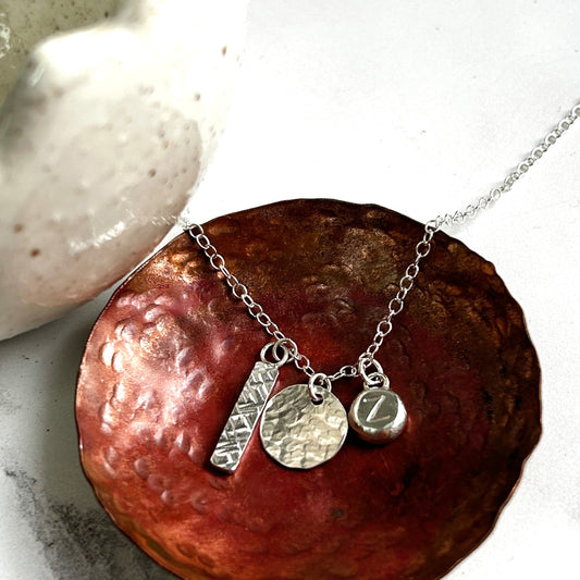 Silver charms necklace with a textured bar, disk and silver pebble with letter Z, by zoe ruth designs