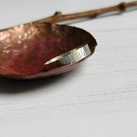 A 5mm wide silver ring with a linear treebark like texture, by zoe ruth designs.