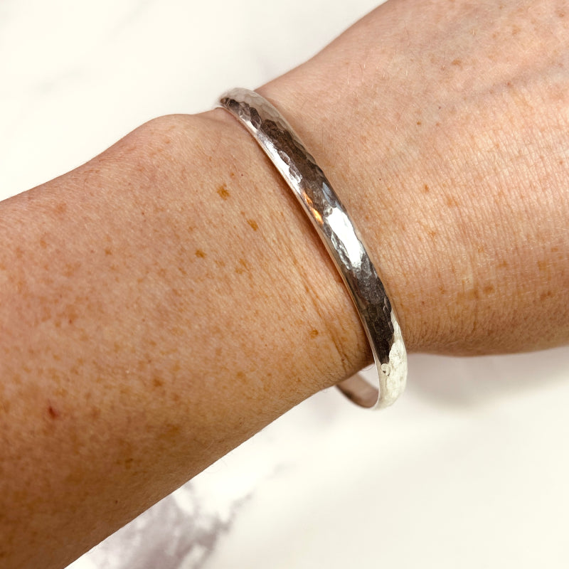 A sterling silver hammered bangle being worn
