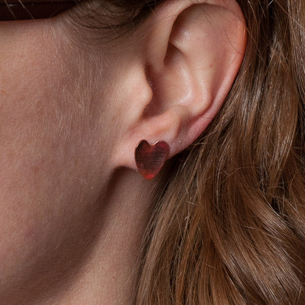 Dark reddish brown copper heart shaped stud earrings, shown being worn, by zoe ruth designs