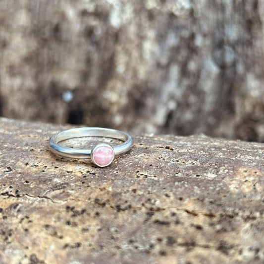 A silver slim smooth band ring with a pale pink rhodochrosite stone set on it, by zoe ruth designs