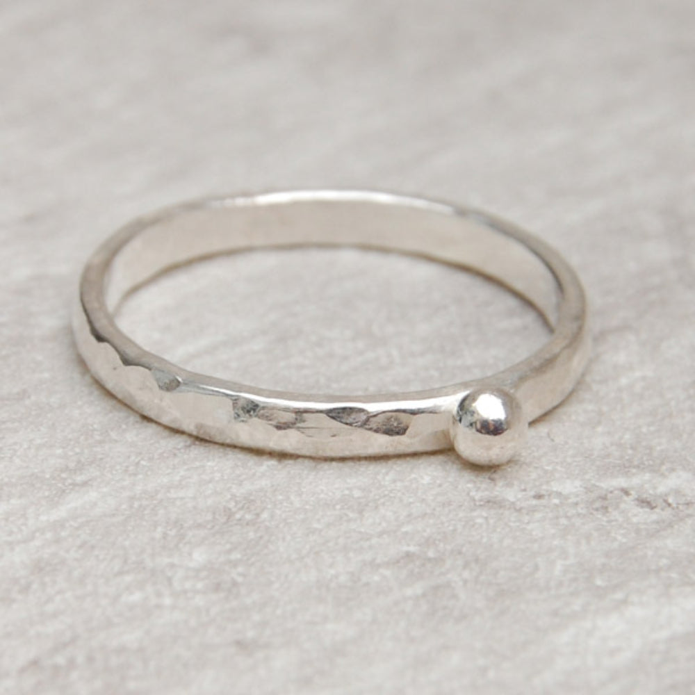 Showing a hammered surface silver slim ring with a single silver small round pebble shape on the surface, by zoe ruth designs