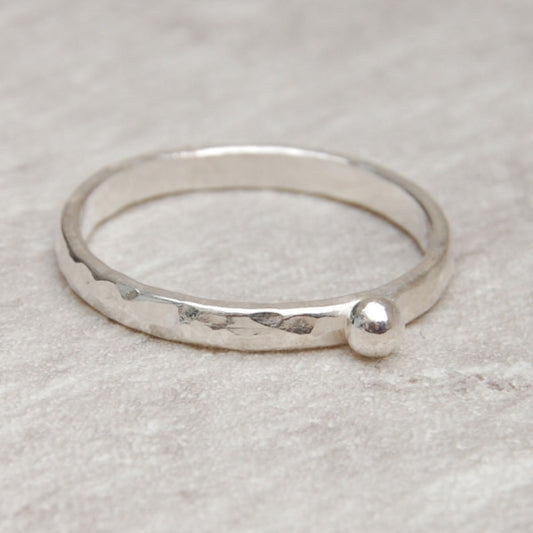 Showing a hammered surface silver slim ring with a single silver small round pebble shape on the surface, by zoe ruth designs