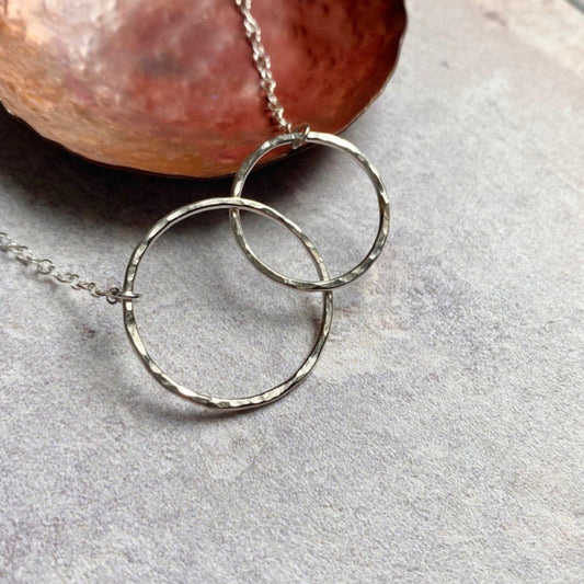 Showing a necklace of two linked hammered silver circles, by zoe ruth designs