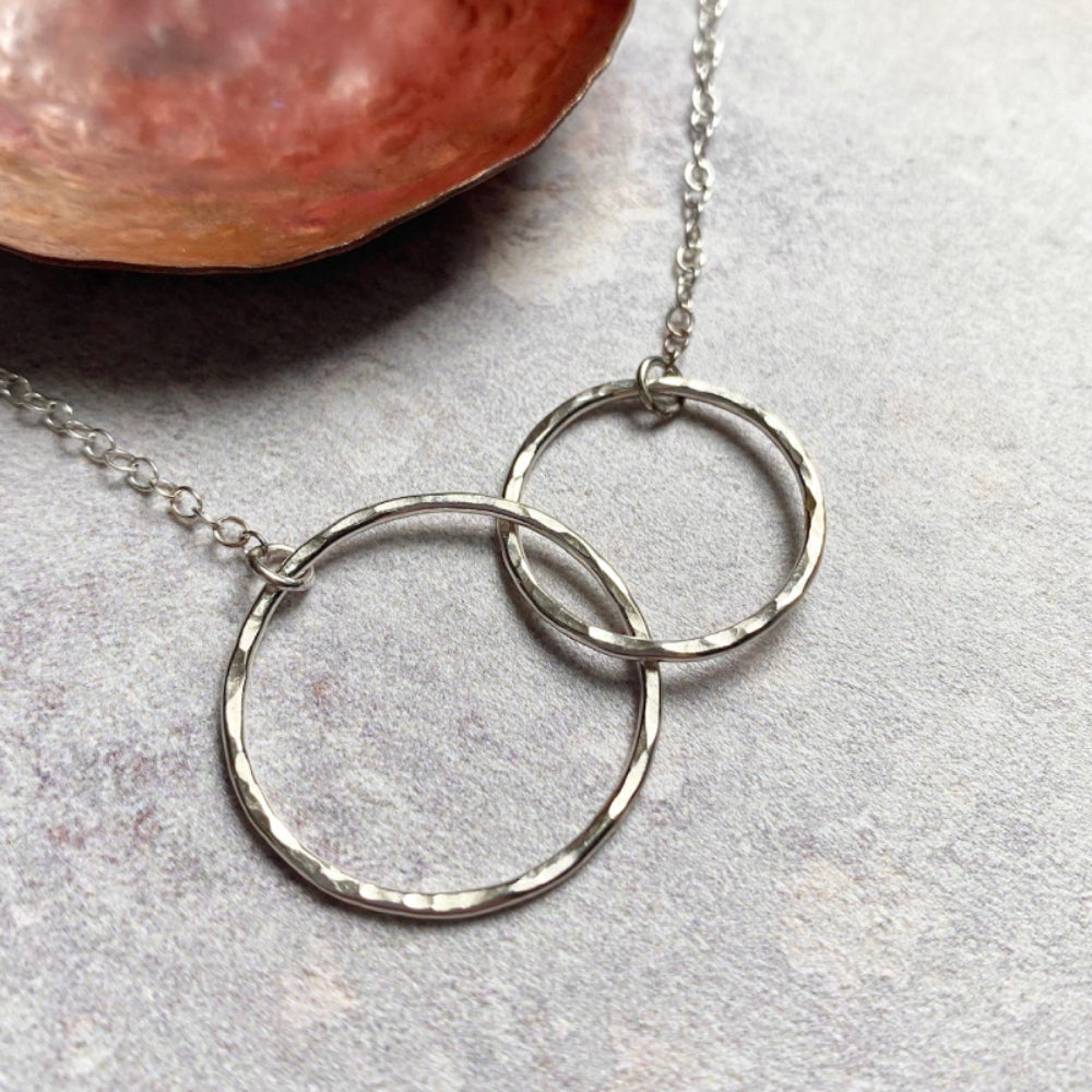 Showing a necklace of two linked hammered silver circles, by zoe ruth designs