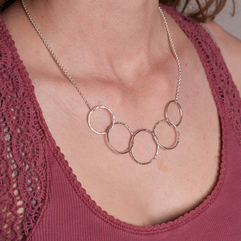 Five hammered silver circles linked into a necklace, a sterling silver chain completes it, shown being worn, by zoe ruth designs