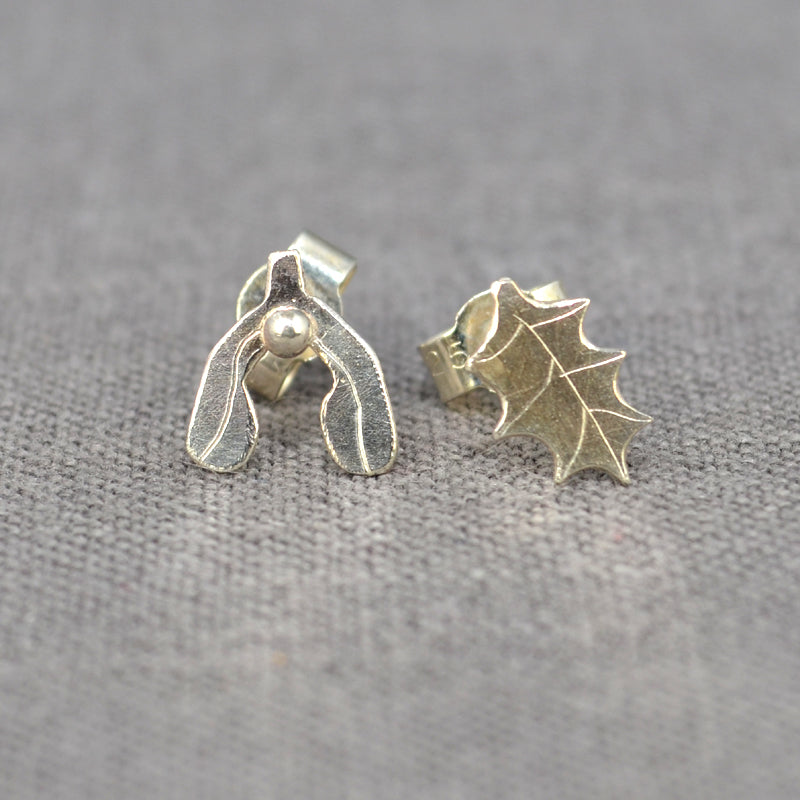A pair of handmade 2D silver earrings, on a holly leaf with detail scribed one, the other a mistletoe leaf with a silver ball as a berry, by zoe ruth designs.