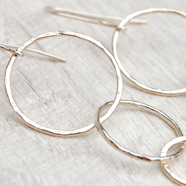 Close up of three silver open circles of decreasing sizes hang from the silver earring hooks, by zoe ruth designs.