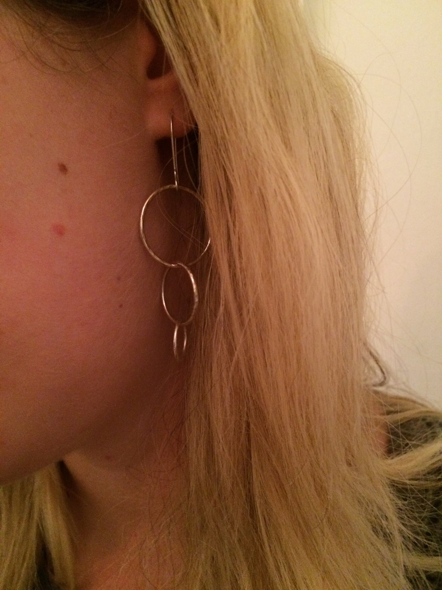 Three silver open circles of decreasing sizes hang from the silver earring hooks, being worn, by zoe ruth designs.