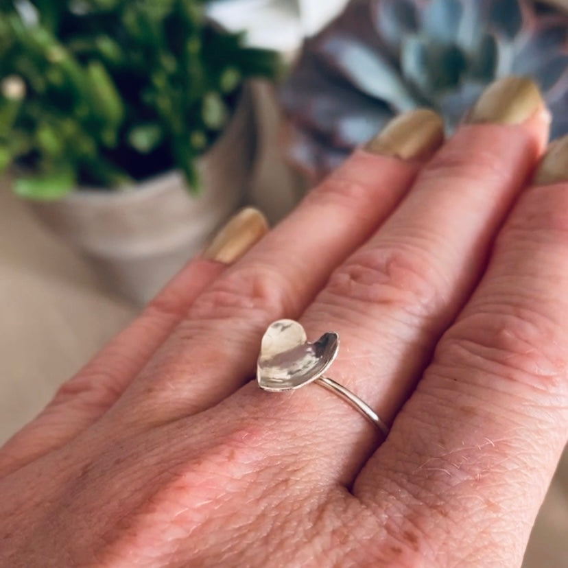 Hammered silver heart on a thin round silver wire ring being worn, by zoe ruth designs