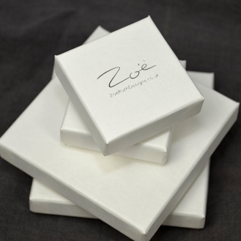 A stack of white gift boxs with the Zoe Ruth Designs logo printed on the top card.