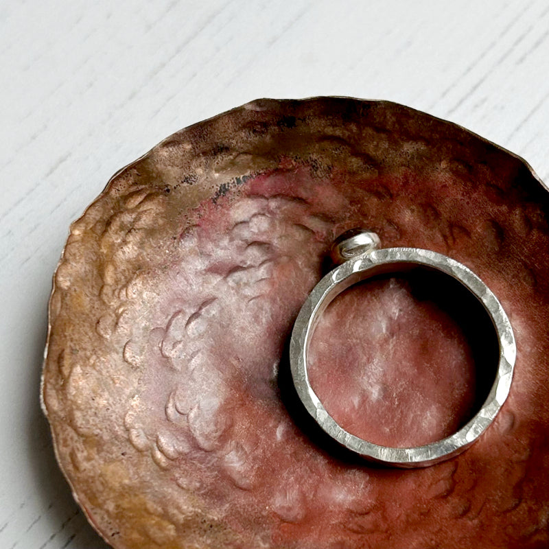 Top view of a handmade silver ring showing the classic dimple texture around the edge