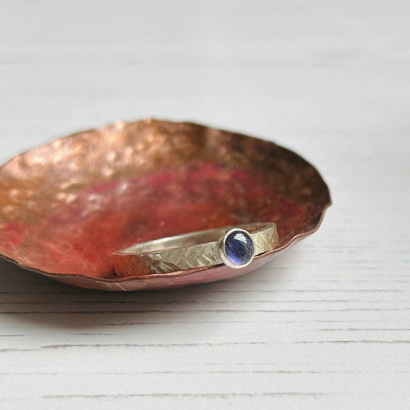 A strong blue iolite stone bezel set on a silver textured ring band