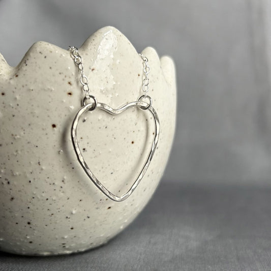 A sterling silver heart outline with a hammered surface sits at the focal point of the necklace, the chain being attacted by jumprings at two moveable places on the heart, by zoe ruth designs