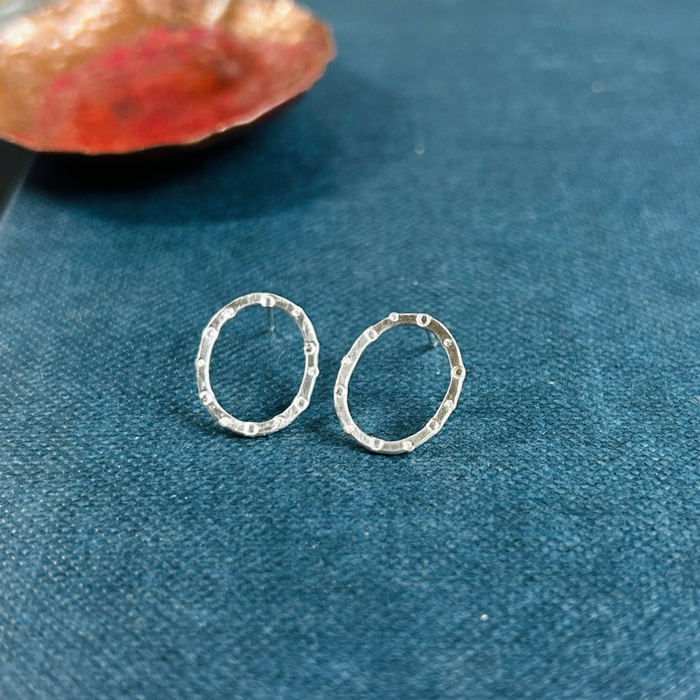 a pair of handmade silver stud earrings, oval in shape with a circle and dot stamped texture by zoe ruth designs