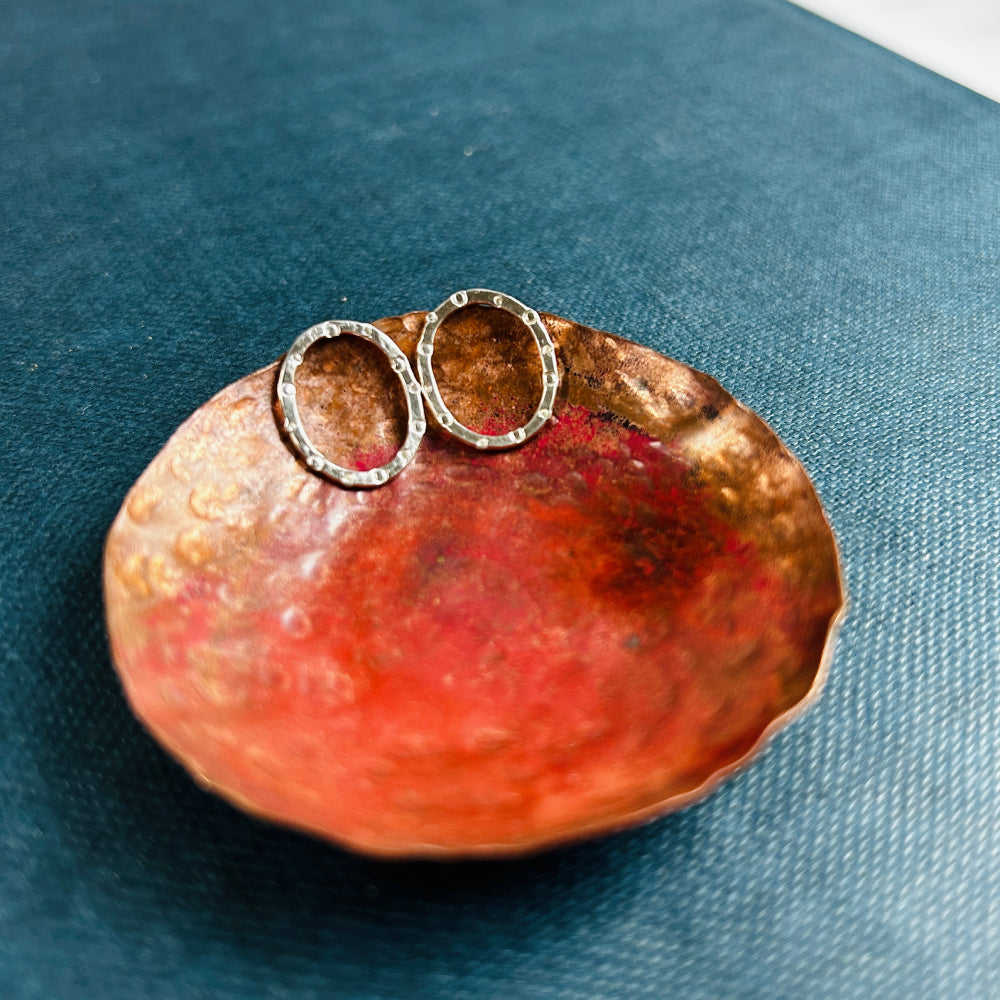 handmade silver stud earrings, oval in shape with a circle and dot stamped texture on a copper dish, all by zoe ruth designs