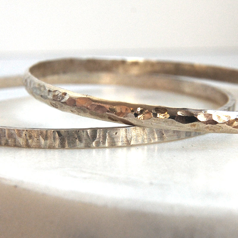 Two different textured handmade bangle next to each other to show the contrast in hammering