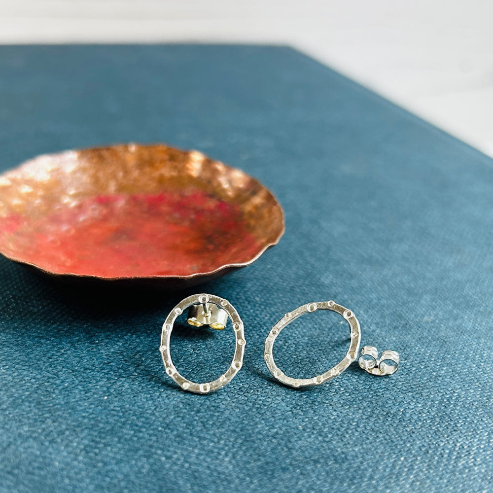 a pair of handmade silver stud earrings, oval in shape with a circle and dot stamped texture by zoe ruth designs