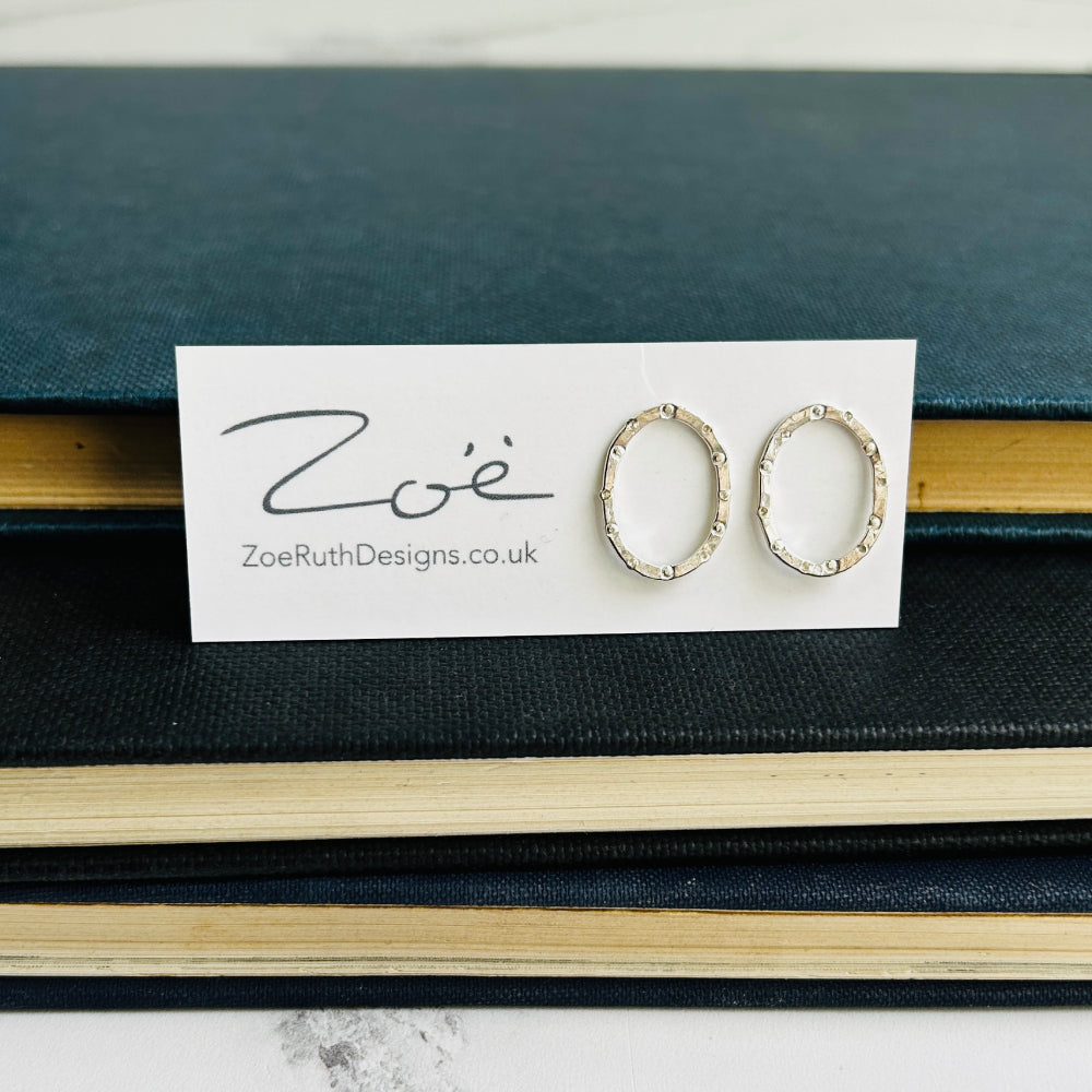 handmade silver stud earrings, oval in shape with a circle and dot stamped texture by zoe ruth designs shown on display card packaging.