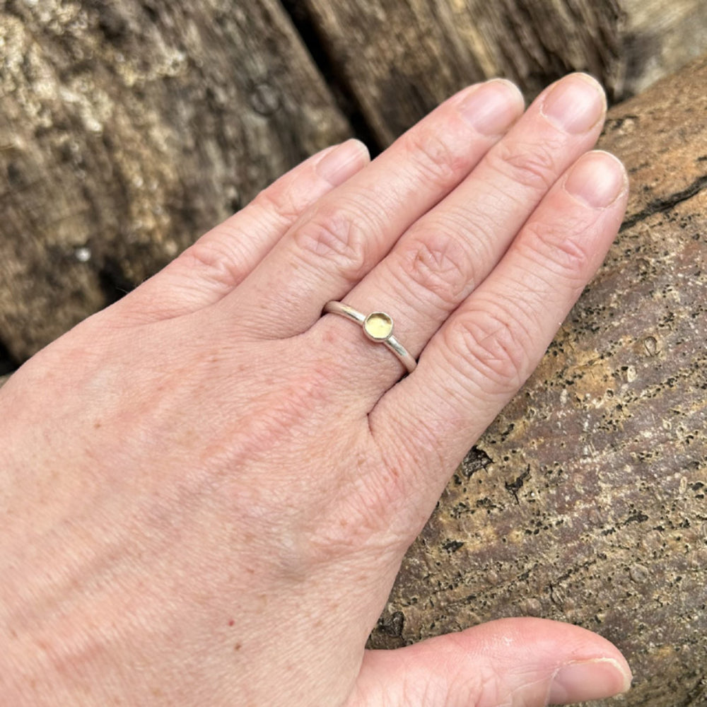 A smooth slim silver ring with a yellow citrine stone set on it shown being worn, by zoe ruth designs