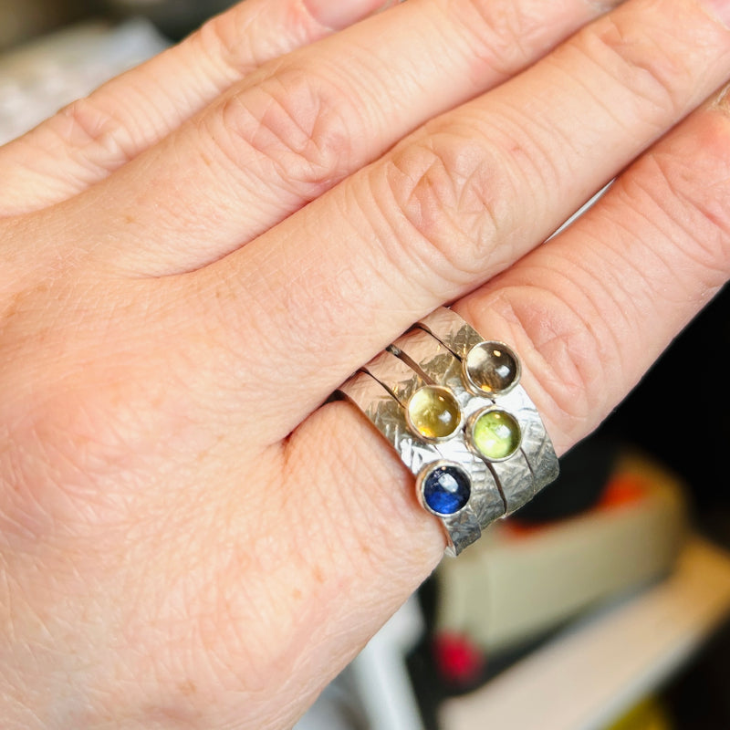 Four criss cross textured silver rings each with different semi precious stones; smokey quartz, peridot, citrine, iolite.