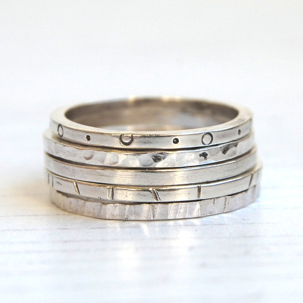 Showing five silver stacking rings with different surface textures, by zoe ruth designs