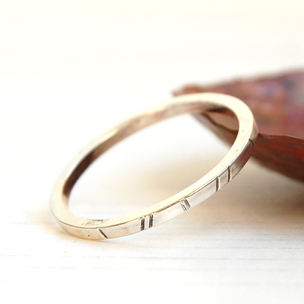 showing a square profile silver wire made into a ring with a geometic lines pattern filed into the surface, by zoe ruth designs