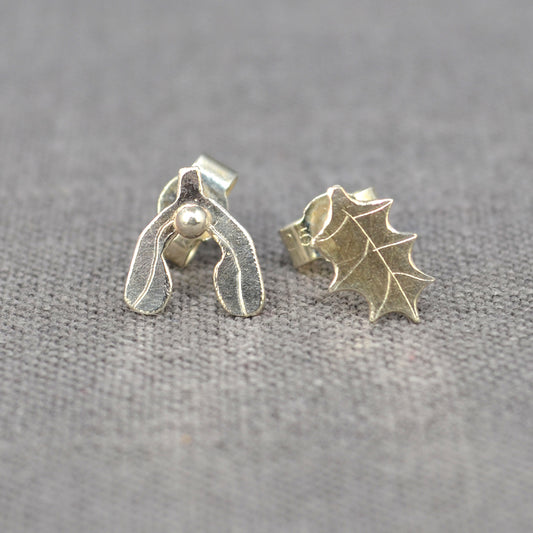 A pair of handmade 2D silver earrings, on a holly leaf with detail scribed one, the other a mistletoe leaf with a silver ball as a berry, by zoe ruth designs.