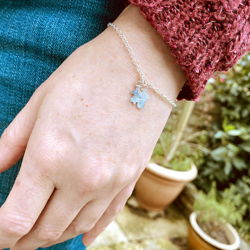 Acorn and oakleaf handmade sterling silver bracelet by Zoe Ruth Designs being worn by lady in garden