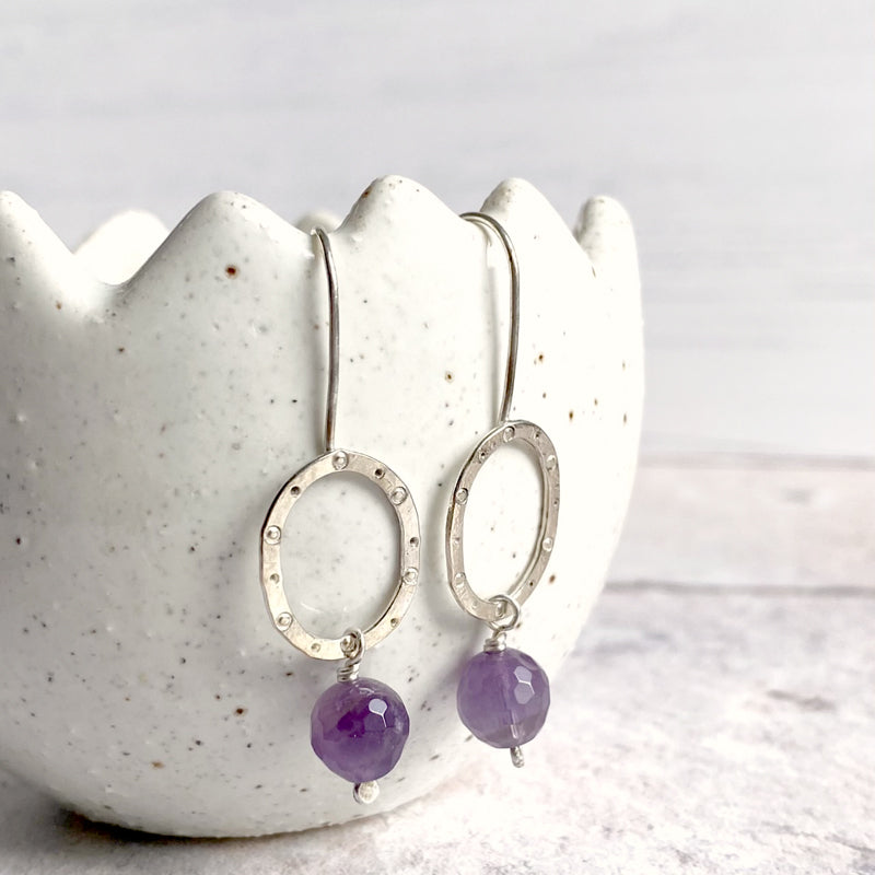 handmade earrings in sterling silver with faceted amethyst hanging under sterling oval made by zoe ruth designs