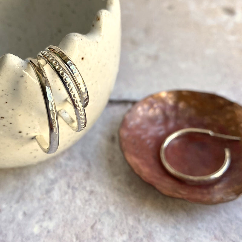 three sterling silver hoop stud earrings showing different textures one out of focus in the background to show shape by zoe ruth designs