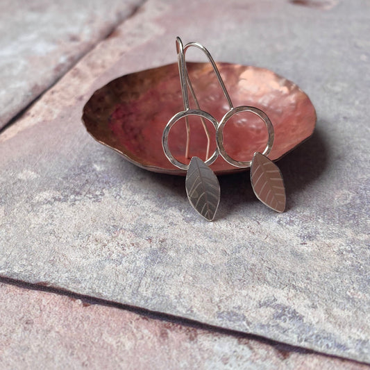 Silver hook earrings, open circle with solid silver leaf shape, scribed leaf detail, by zoe ruth designs.