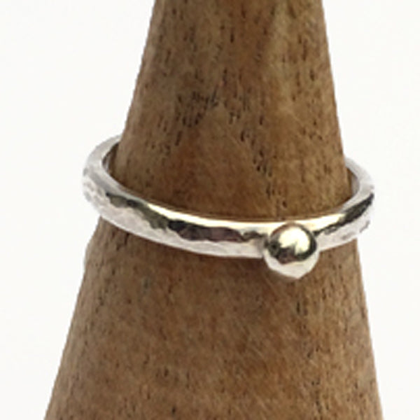 Showing a hammered surface silver slim ring with a single silver small round pebble shape on the surface, by zoe ruth designs