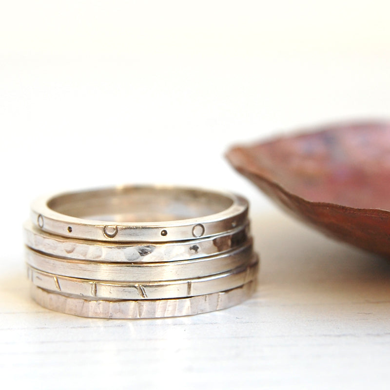 a stack of five handmade textured silver rings and copper dish by zoe ruth designs